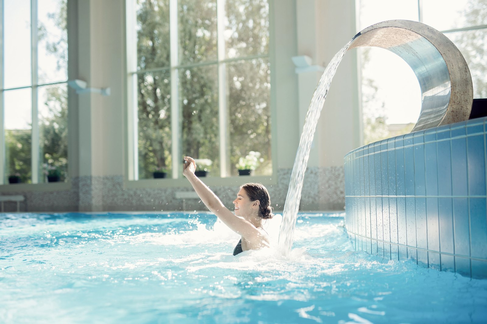 Client enjoying an indoor wellness pool with a waterfall feature
